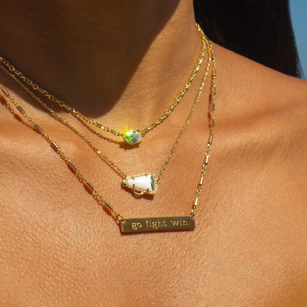 Gold necklaces with gemstones and a bar necklace on a person's neck
