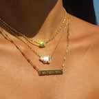 Gold necklaces with gemstones and a bar necklace on a person's neck
