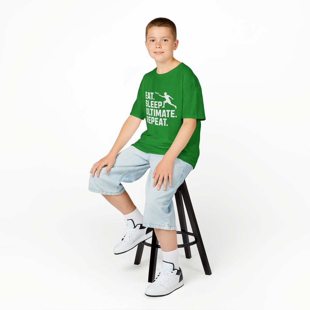 Child wearing a green t-shirt with text, sitting on a stool against a white background
