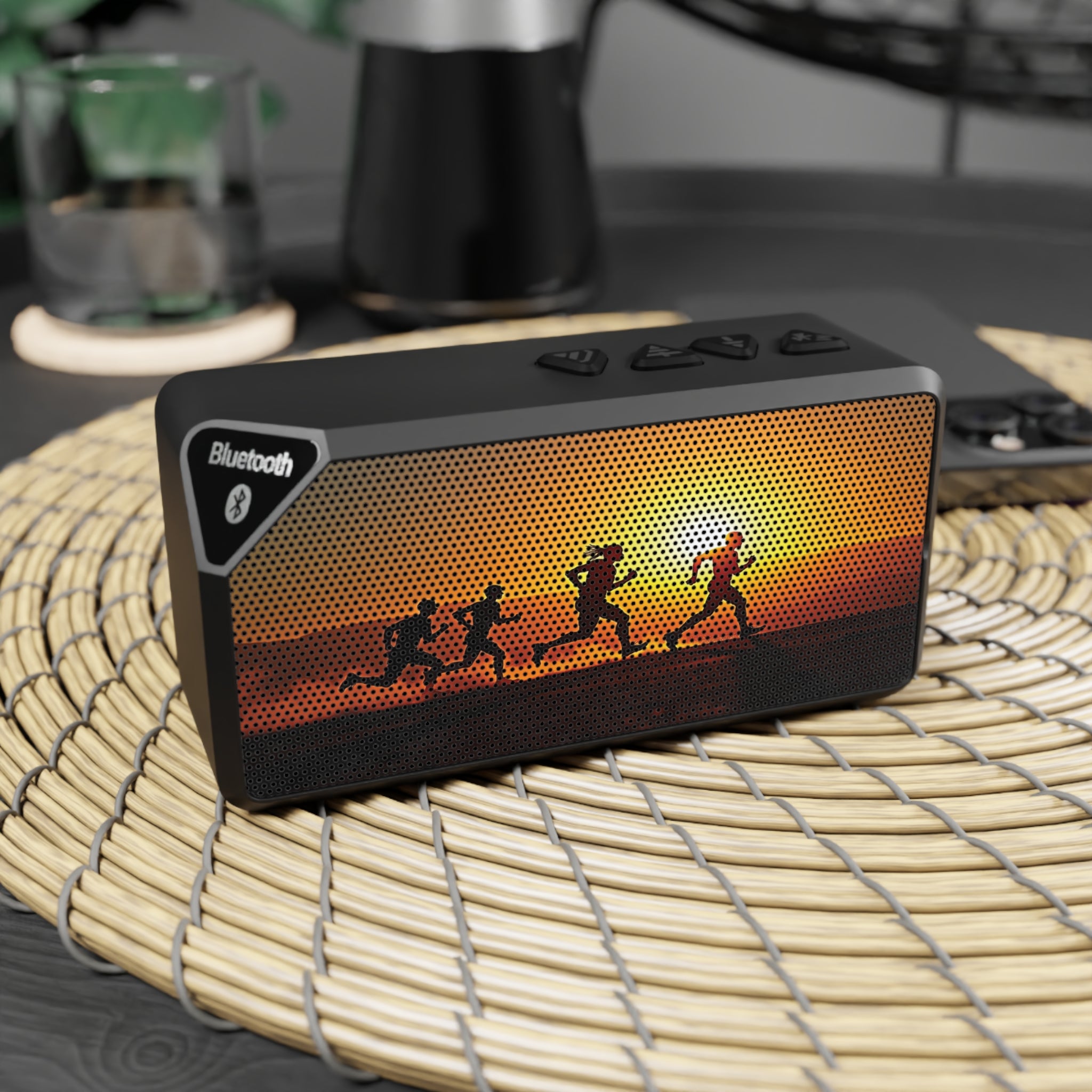 Black Bluetooth speaker with sunset design on a woven mat