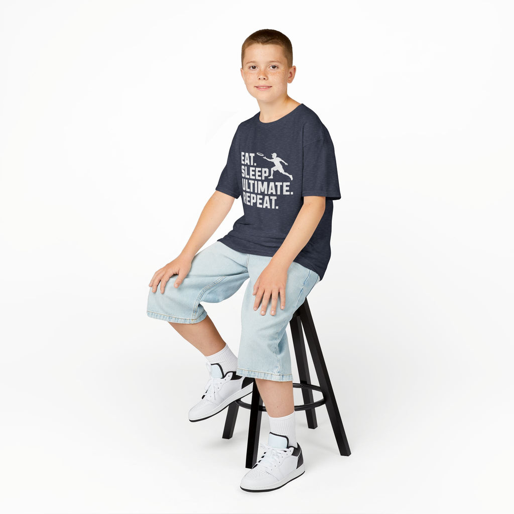 Child sitting on a stool wearing a navy t-shirt with white text and light blue shorts on a white background