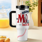 White tumbler with black handle and 'BASEBALL MOM: Snack Shack MVP' design on a blurred background