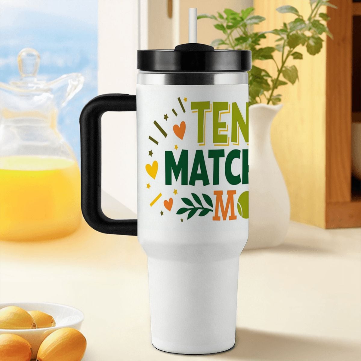 White travel mug with colorful "Tennis Match Day Mom" text and black handle on a kitchen counter.