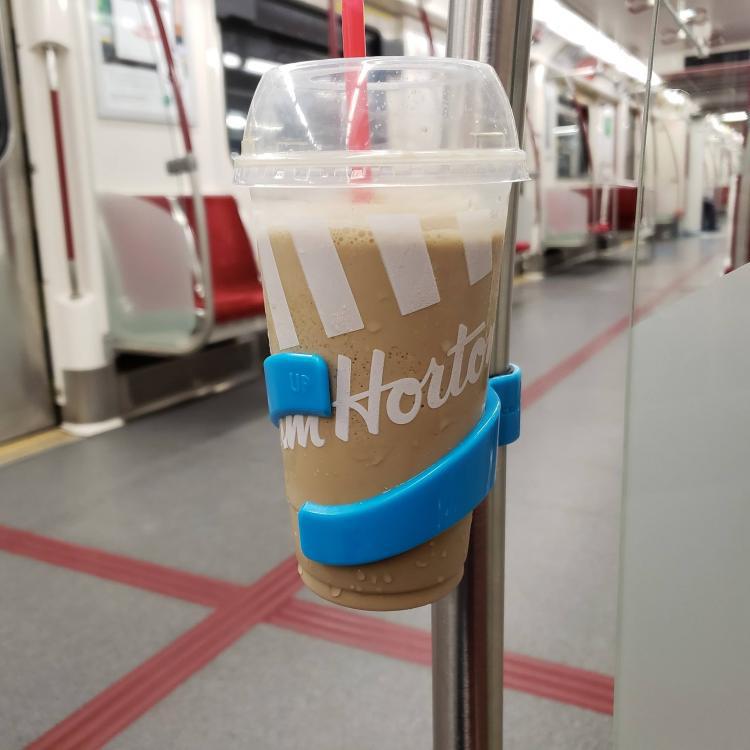 Tim Horton's iced coffee cup with a blue holder on a pole inside a train