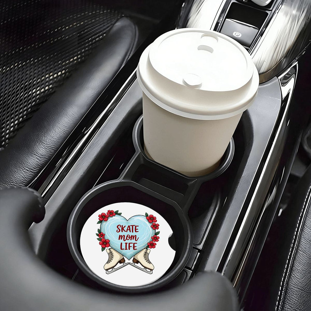 Car cup holder with a white coffee cup and a decorative coaster featuring a heart design.