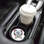Car cup holder with a white coffee cup and a decorative coaster featuring a heart design.