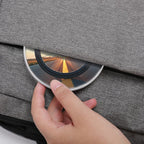 Hand opening a gray fabric case to reveal a reflective disc with a scenic image.