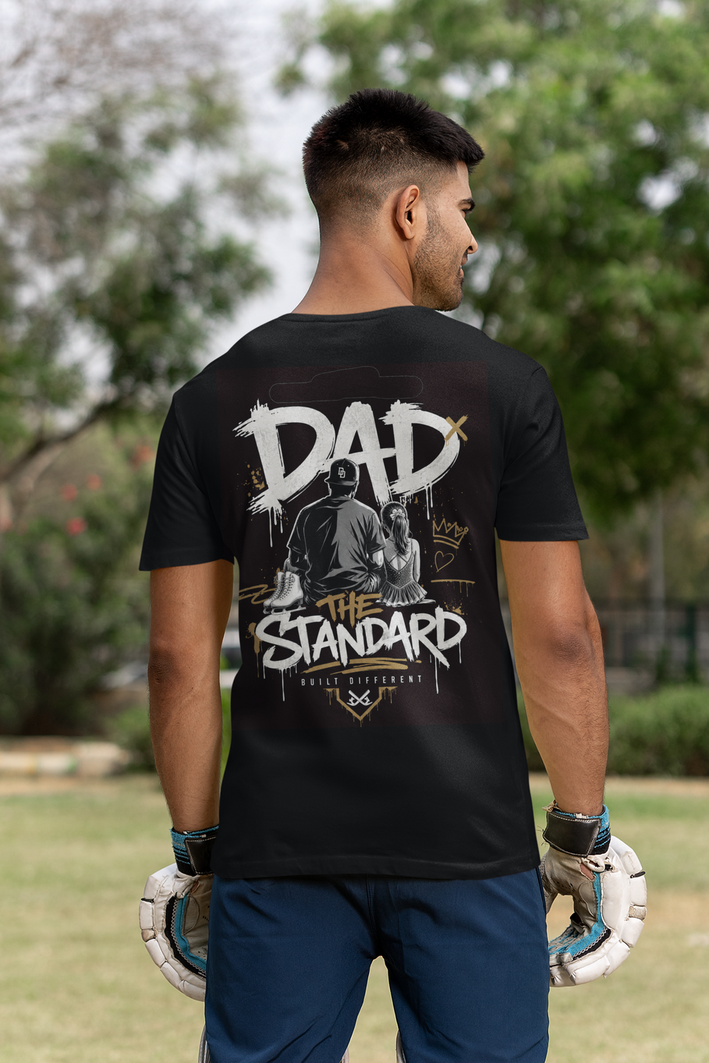 Man wearing a black t-shirt with 'DAD THE STANDARD' girl figure skating design outdoors.