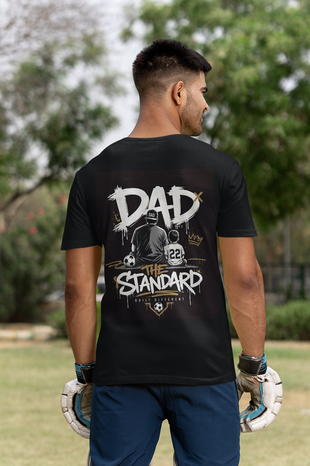 Man wearing a black t-shirt with a soccer father's day streetwear themed graphic design outdoors