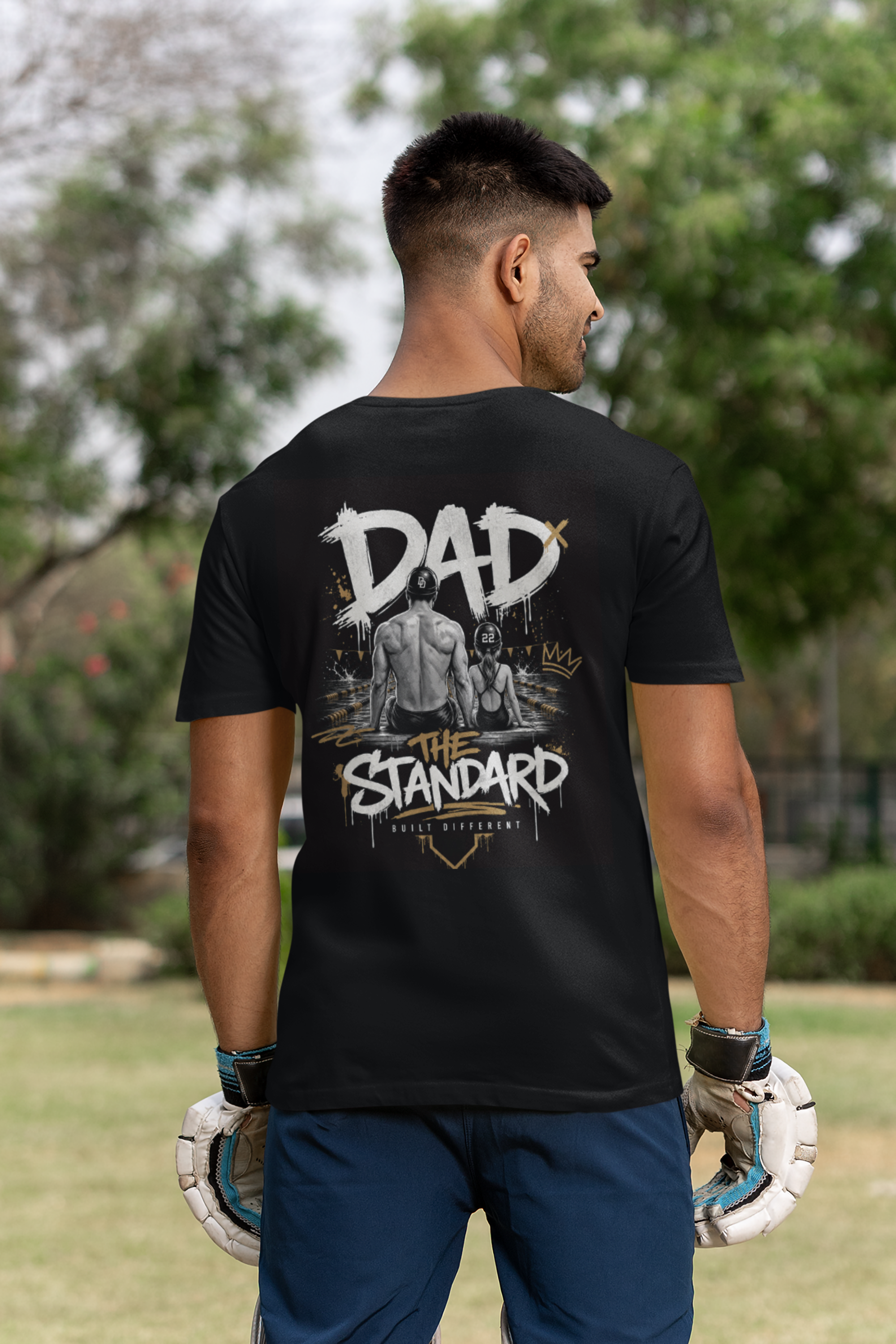 Man wearing a black t-shirt with 'DAD THE STANDARD' female swimming design outdoors