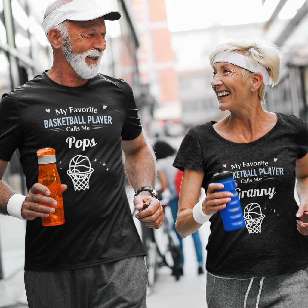 Man and woman walking together wearing matching t-shirts with humorous text about basketball and family.